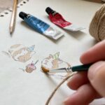 An artist painting guinea pigs or hamsters for a birthday card
