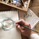 An artist using watercolours to paint two owls