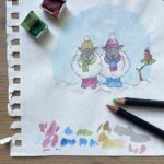 An artist drawing two winter sheep for a greetings card