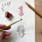 An artist illustrating a children's 1st birthday card design