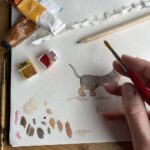 An artist painting a dog with watercolour