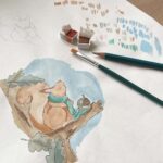 An artist illustrating a red squirrel for a Christmas card