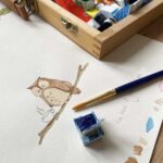 An artist drawing an owl design for a card