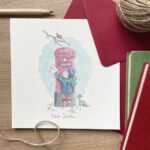 A Christmas card for children depicting a child posting a letter to Santa in a snowy scene
